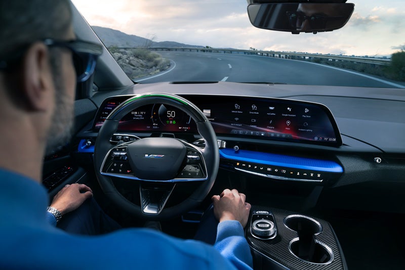 Front View of the 2026 OPTIQ-V Driving Through the Dusk Utilizing its Headlights | Miller Brothers Cadillac in Ellicott City MD